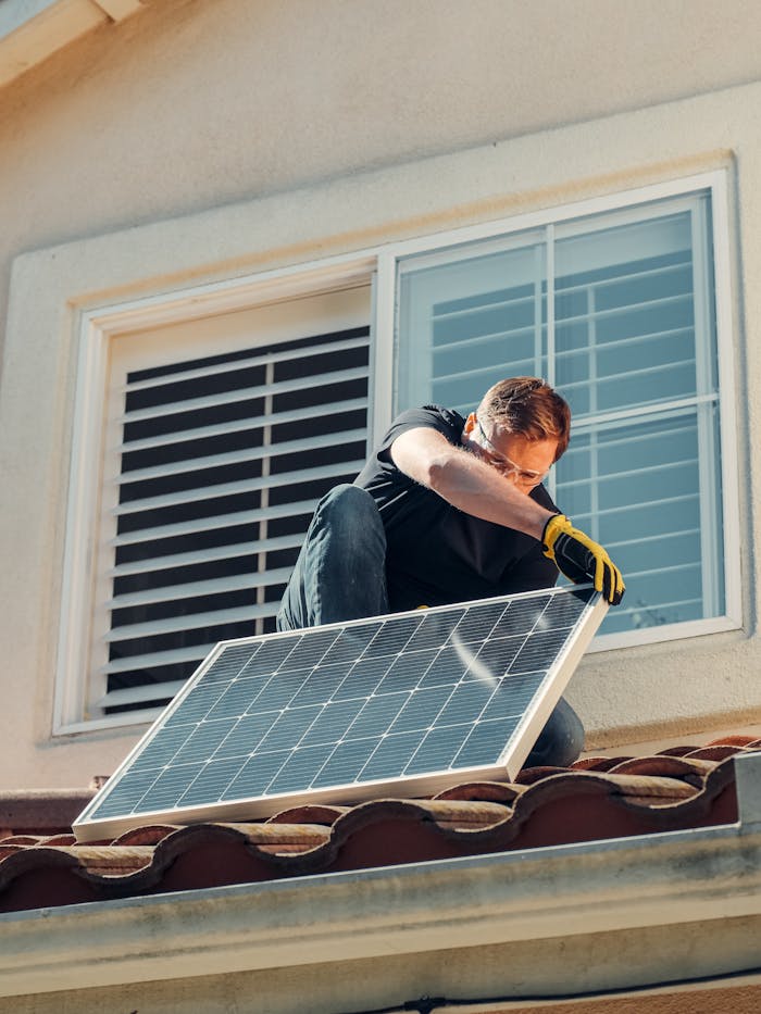 Man installing a solar panel on a residential rooftop, promoting sustainable energy.